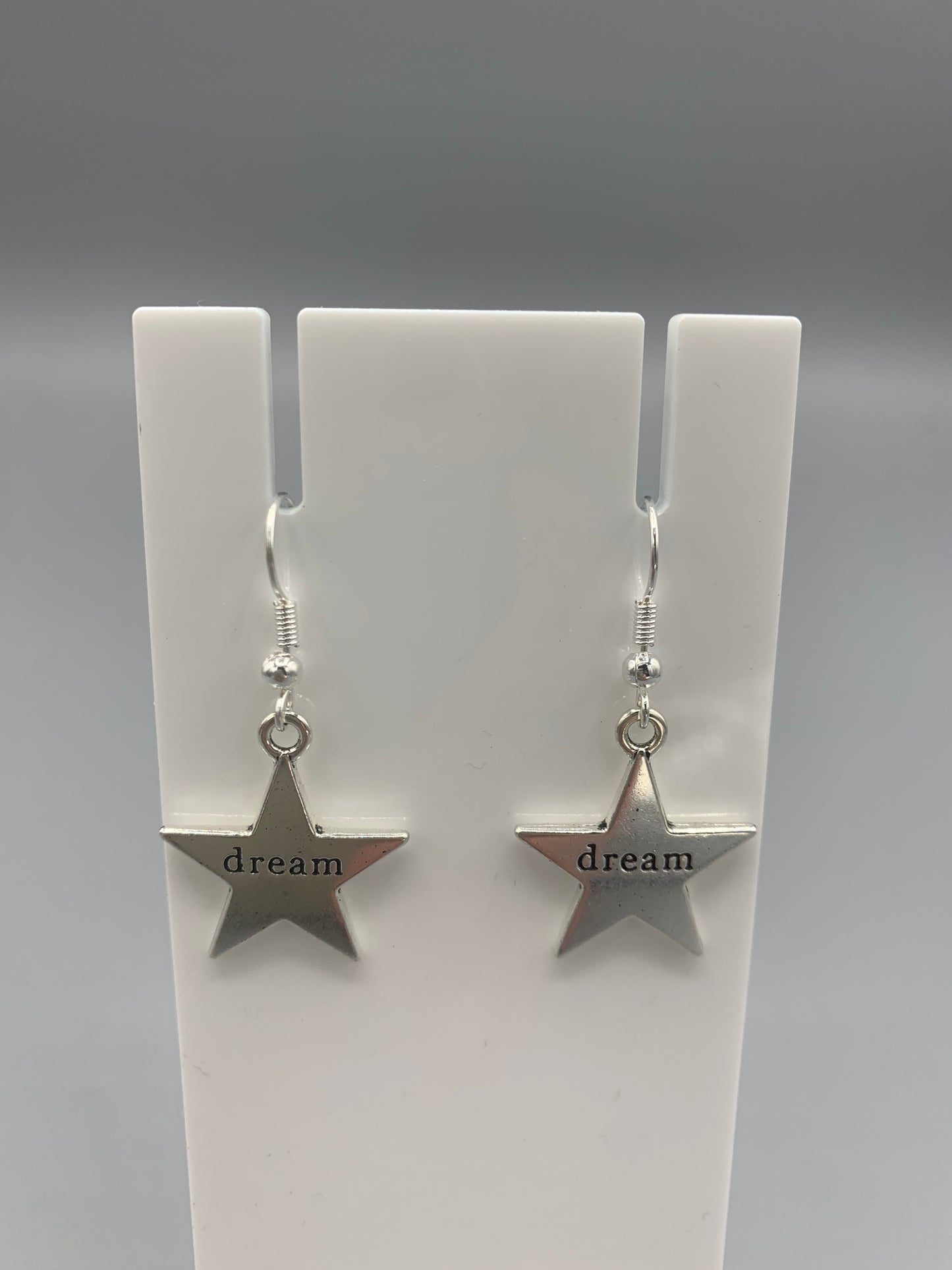 Large star silver coloured alloy charm with the word dream embossed across the centre on silver plated hooks. Hamilton earrings. Dream earrings.