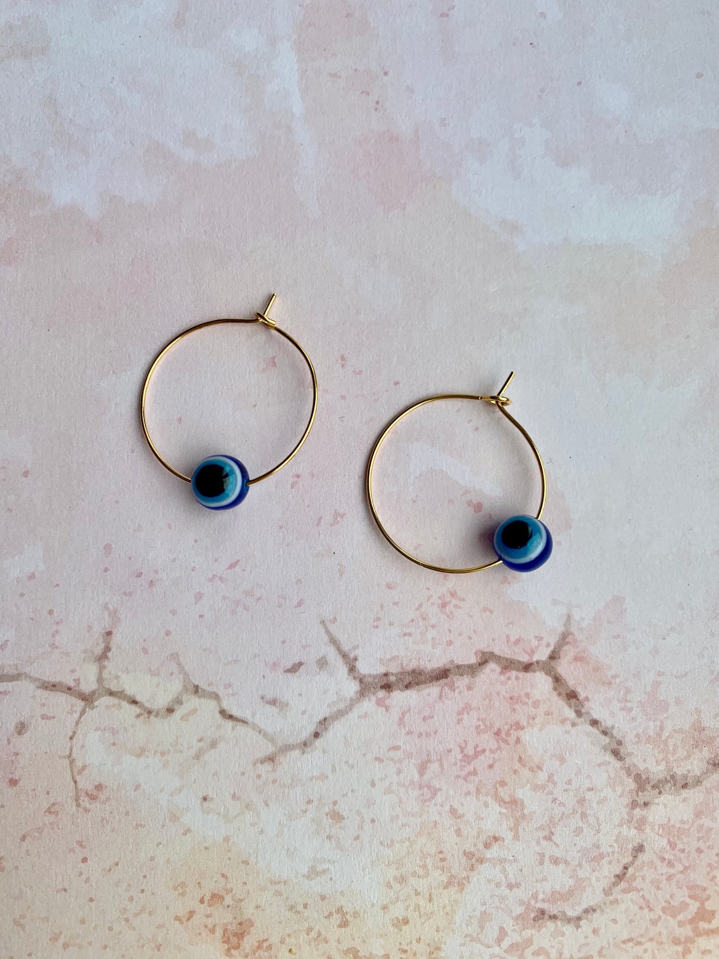 Small evil eye spherical bead on gold plated hoop earrings. Colours from outside to inside of the evil eye are dark blue, white, light blue, black. Hoop earrings. Spiritual earrings. Earrings for women.