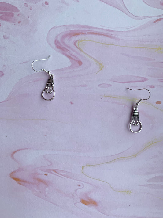 An alloy silver coloured charm that is the outline of a round light bulb on silver plated hooks. Novelty earrings. Great gift for people that are creative or writing a book.