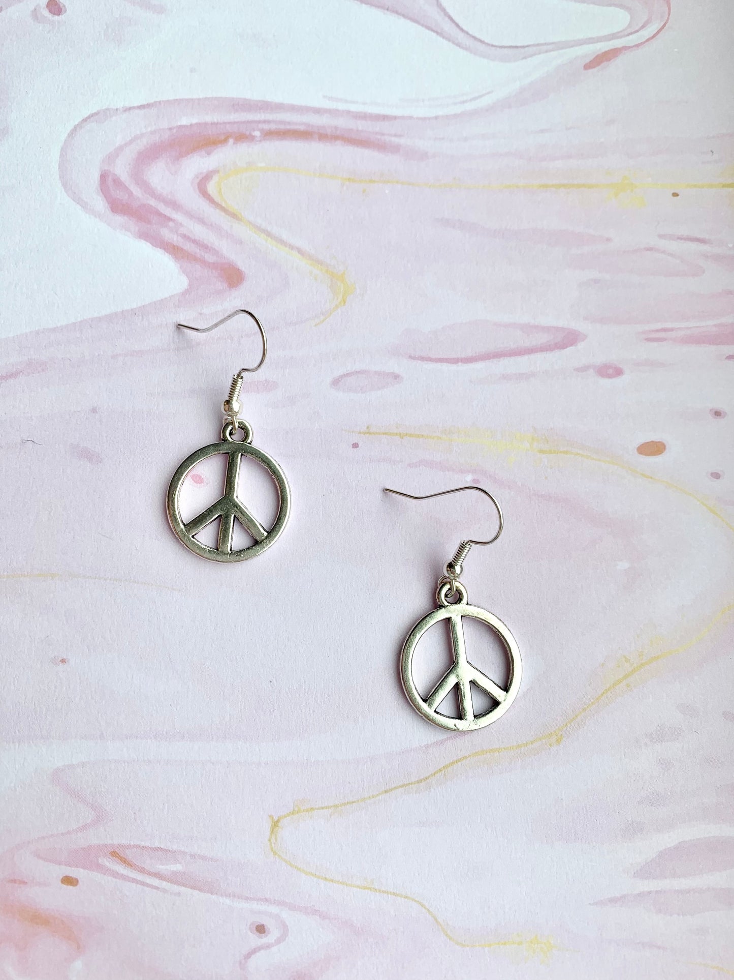 peace earrings. peace symbol silver coloured charm on silver plated hooks. dangle earrings. peace not war. statement earrings.