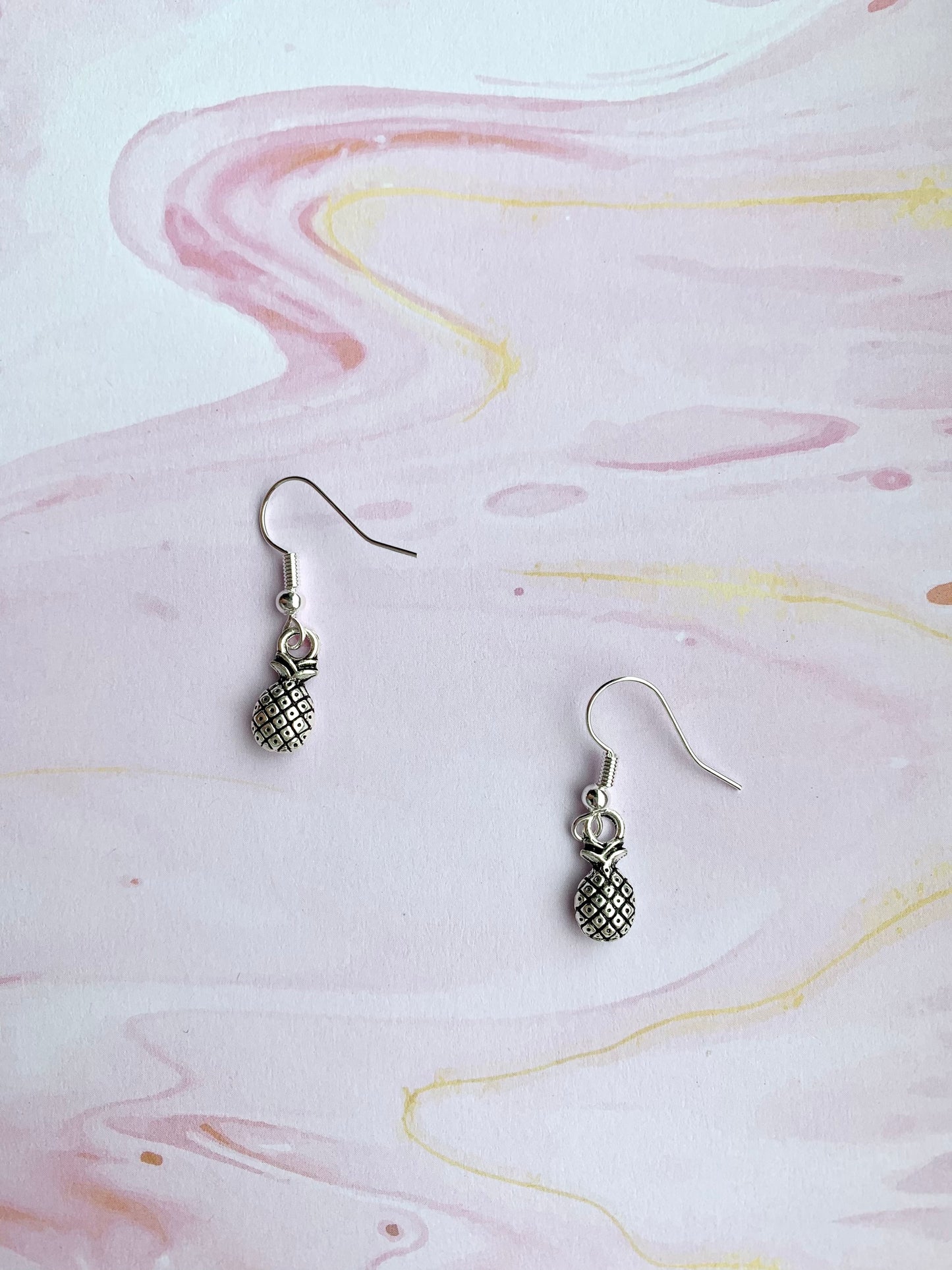 Super cute pineapple earrings. Small silver coloured pineapple charm on silver plated hooks. dangle earrings. popular earrings. cheap earrings.