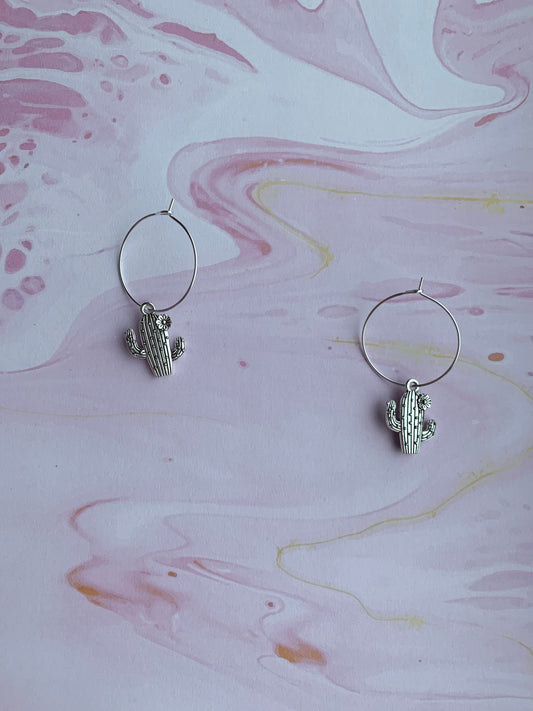 Dangly novelty earrings. Silver coloured alloy cacti charms with spikes and flower on silver plated hoops. Cheap cute earrings.