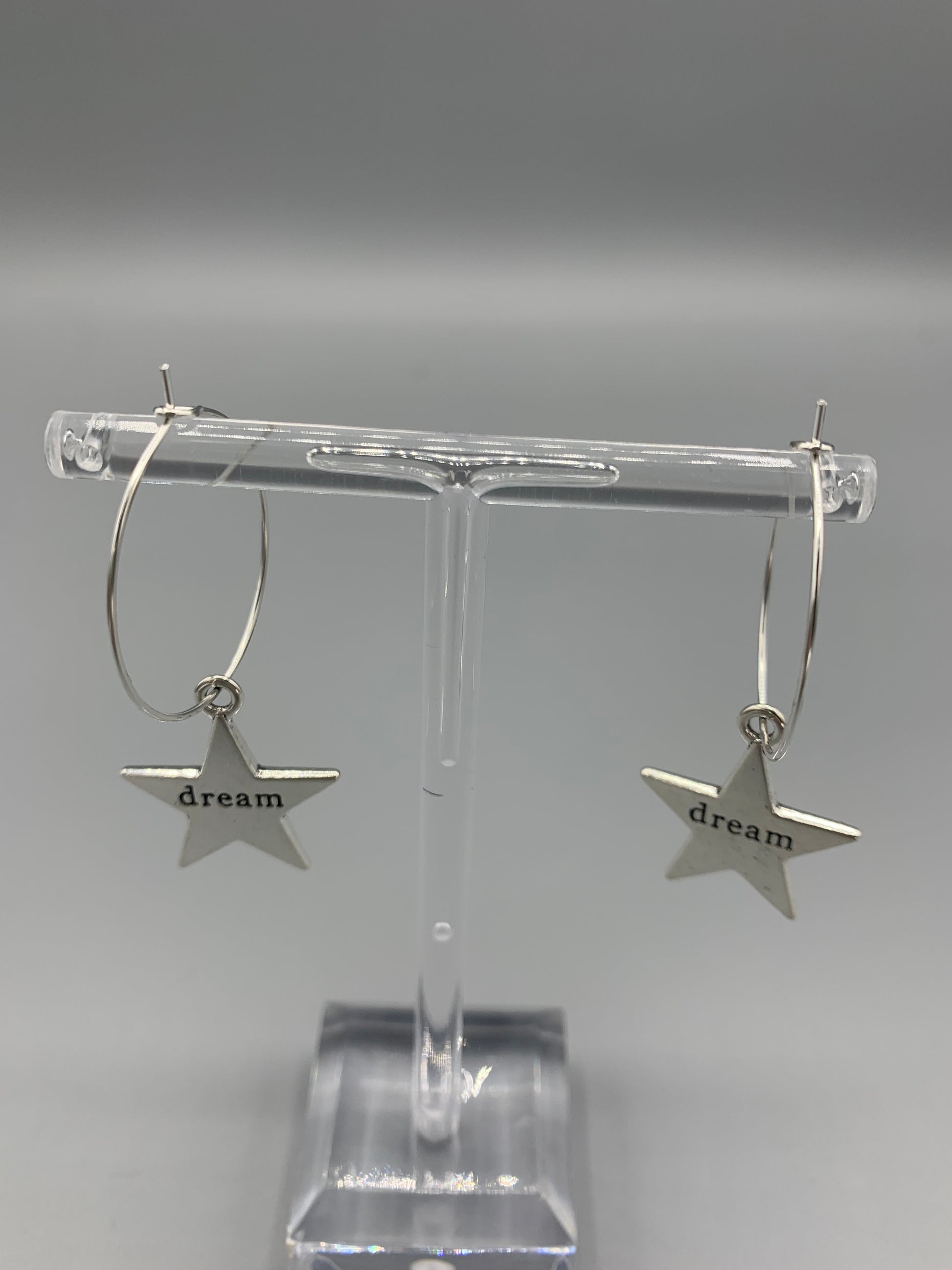 Large star silver coloured alloy charm with the word dream embossed across the centre on silver plated hoops. Hamilton earrings. Dream earrings. buy earrings. 